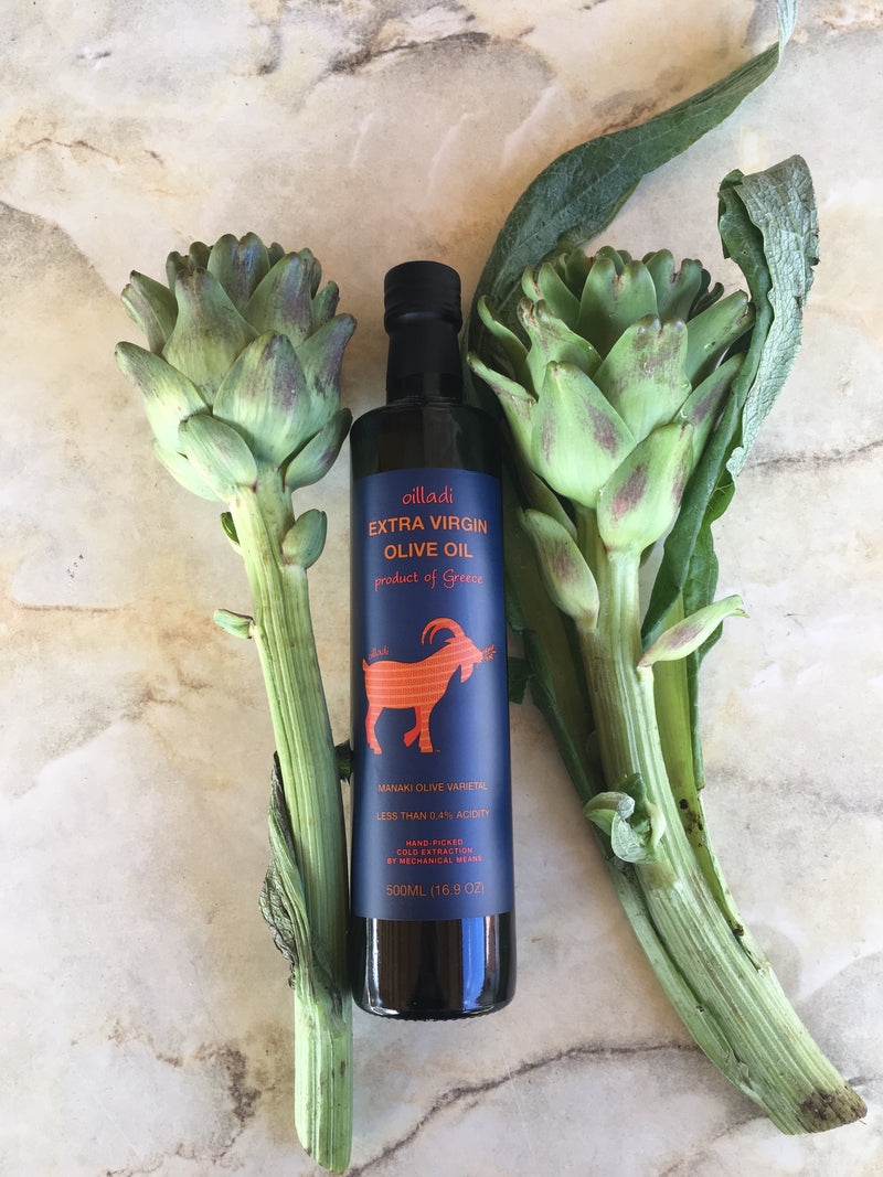 A bottle of Oilladi extra virgin olive oil in between two artichokes on their stems