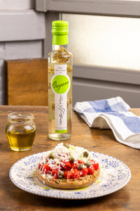 Bottle of Messino White Wine Vinegar with Oregano and plated bruschetta in the foreground