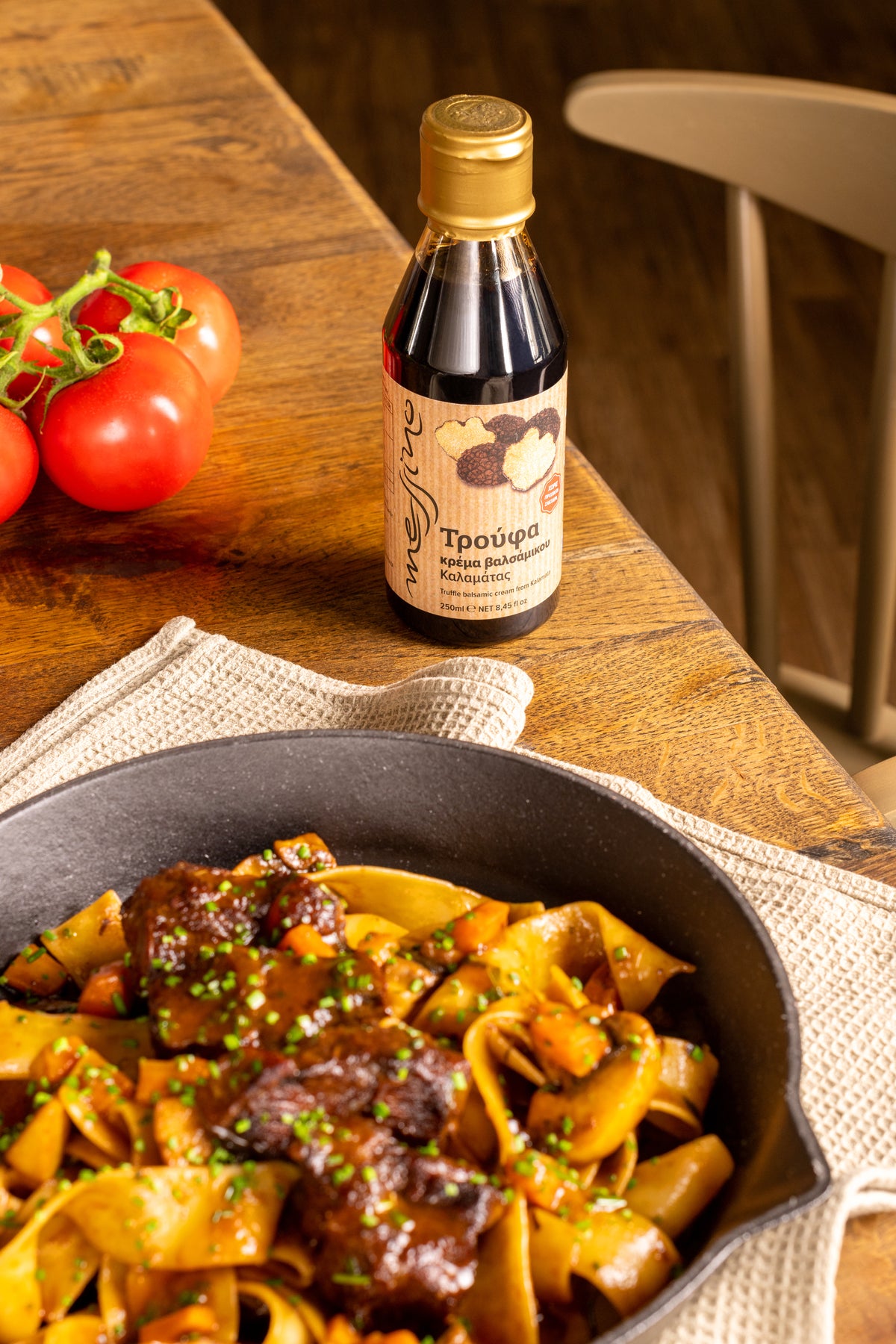 Pasta dish with a bottle of Messino truffle balsamic glaze on a wooden table