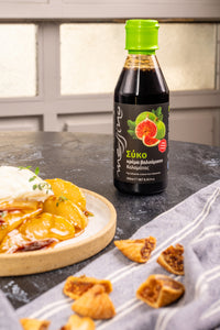 Bottle of Messino Fig Balsamic Glaze next to fruit and yogurt on a table