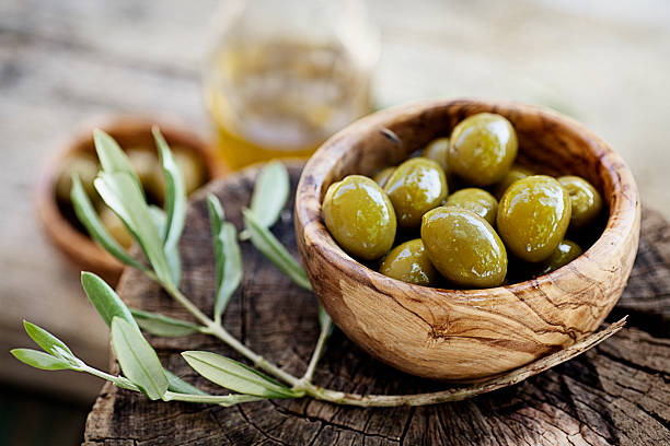 Bowl of olives next to a small olive branch