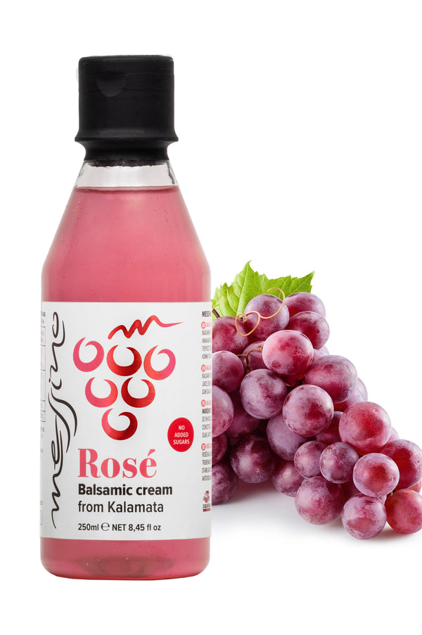 Bottle of Messino rose balsamic cream with grapes on a white background