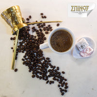 Spilled coffee beans next to cup of greek coffee and sweets