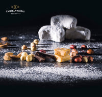 Chrisanthidis Kourabie cookies in the background with nuts and chocolate sprinkled with powdered sugar in the foreground