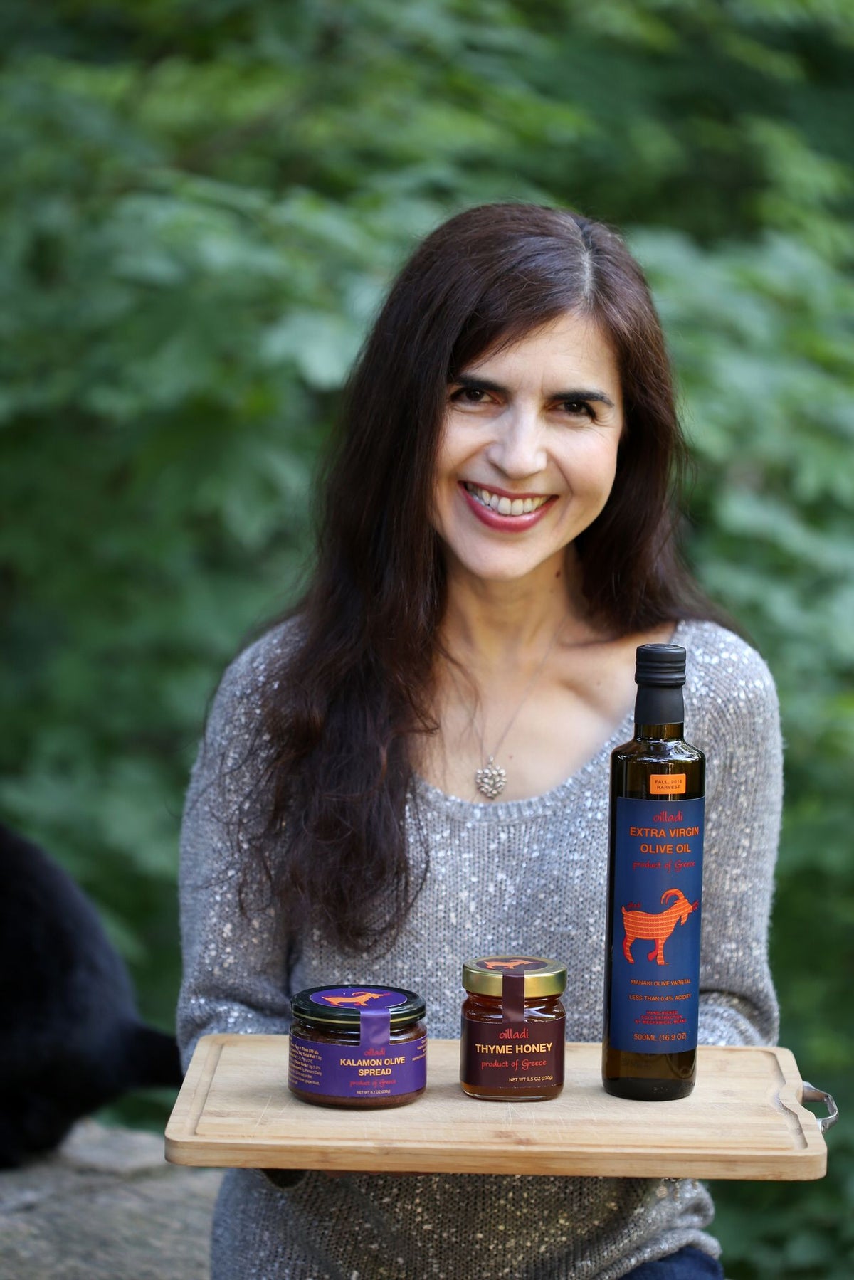 Woman holding tray of Oilladi products including olive spread, thyme honey and extra virgin olive oil