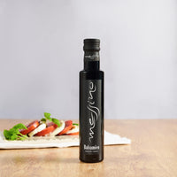 Bottle of Messino Balsamic Vinegar with caprese salad in the background