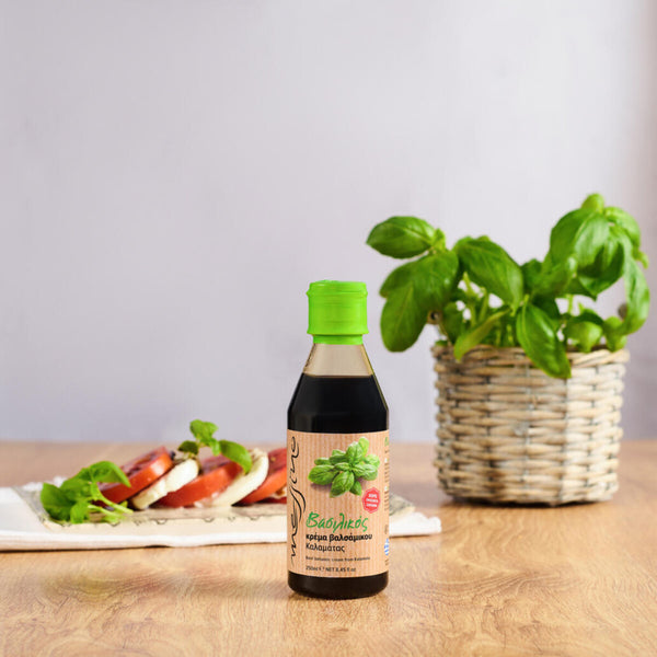 Bottle of Messino Balsamic Glaze with Basil and caprese salad in the background