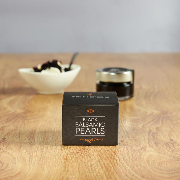 Box of Messino Black Balsamic Pearls and bowl of ice cream in the background next to jar of pearls