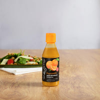 Bottle of Messino Balsamic Glaze with Orange and plated salad in the background