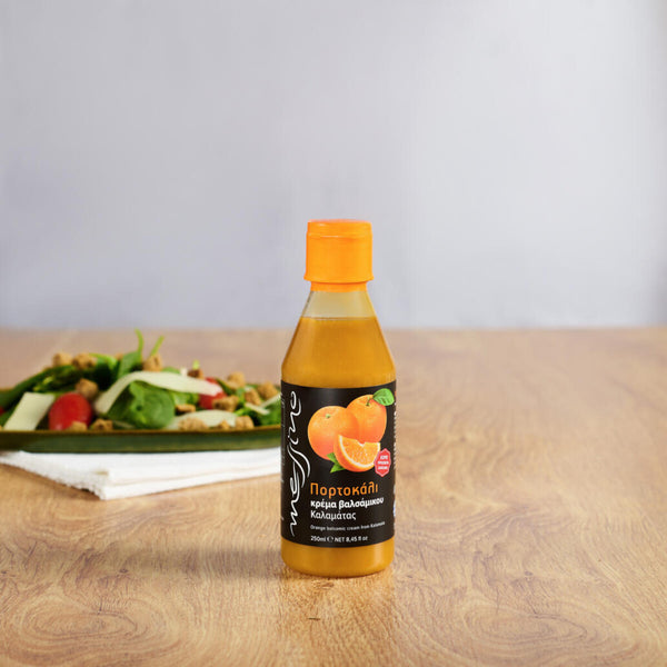 Bottle of Messino Balsamic Glaze with Orange and plated salad in the background