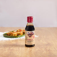 Bottle of Messino Smoked Balsamic Glaze and bruschetta in the background