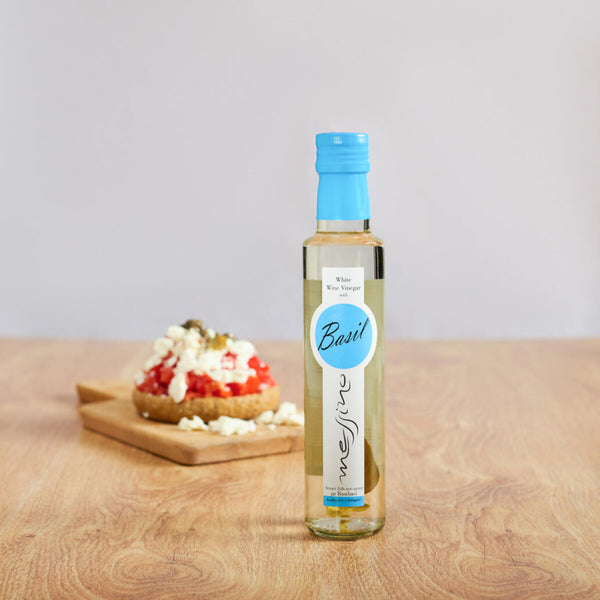 Bottle of Messino White Wine Vinegar with Basil and bruschetta in the background