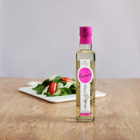 Bottle of Messino White Wine Vinegar with Rosemary and plated salad in the background