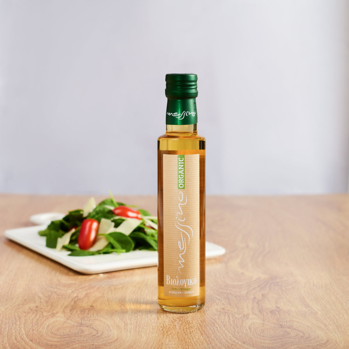 Bottle of Messino Organize White Wine Vinegar and plated salad in the background