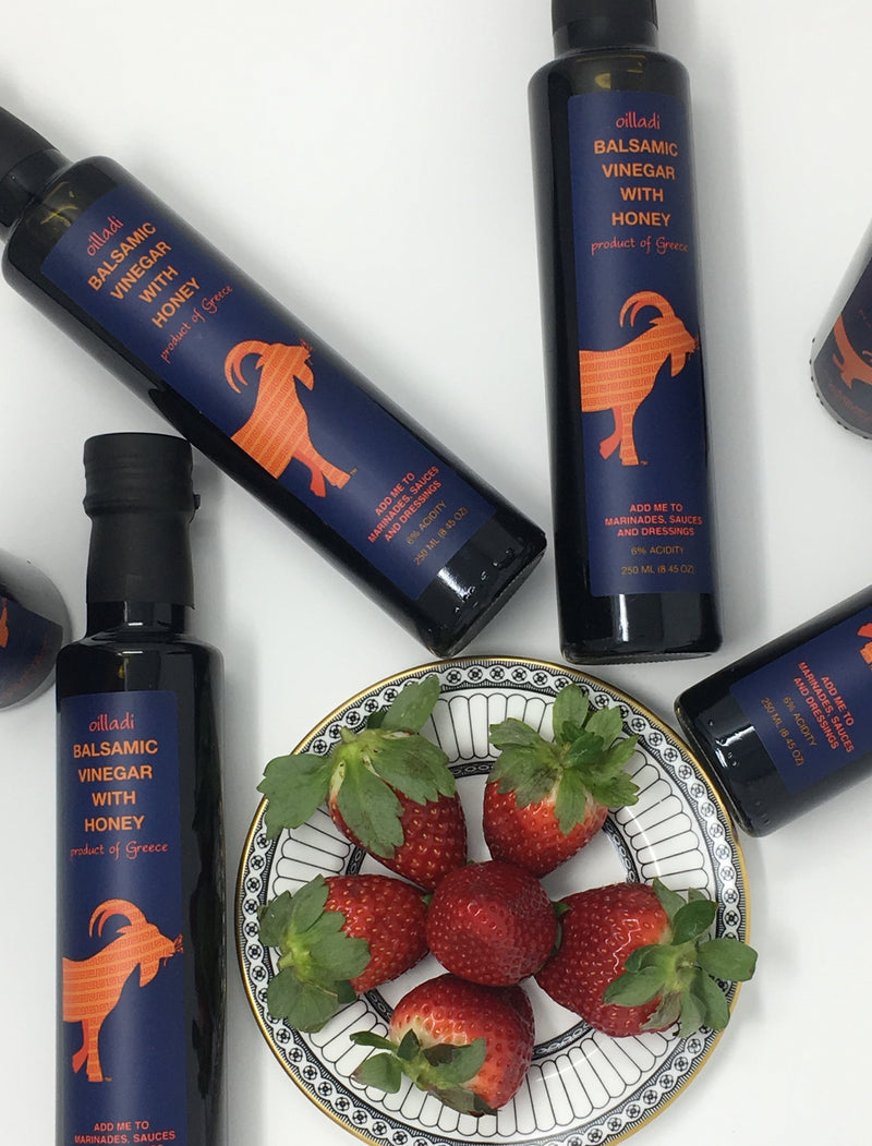 Plate of strawberries surrounded by bottles of Oilladi balsamic vinegar with honey