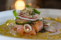 Plated salmon topped with salad and Messino White Balsamic Pearls