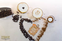 Coffee beans and grains in a heart shape next to 3 cups of cappucino